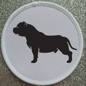 May include: A white round patch with a black silhouette of a pit bull terrier dog.