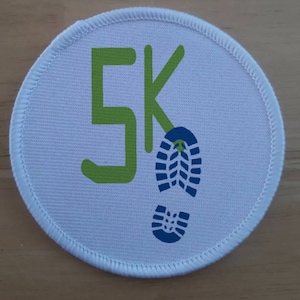May include: White round patch with a green "5K" and a blue footprint graphic.