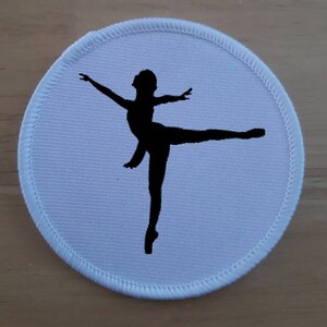 Könnte beinhalten: Runder Stoff-Patch in Weiß mit einer schwarzen Silhouette einer Ballerina in einer Tanzpose.