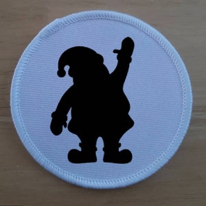 May include: White fabric patch with a black silhouette of Father Christmas with a raised hand.
