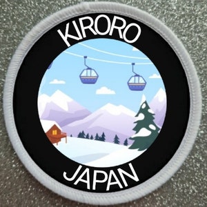Puede incluir: Un parche redondo blanco y negro con las palabras "Kiroro Japan" y una imagen de dibujos animados de una escena de montaña nevada con remontes.