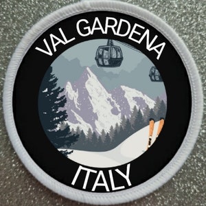 May include: A white and black circular patch with the text "VAL GARDENA ITALY" and a graphic of a snowy mountain scene with a ski lift and skiers.