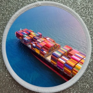 Könnte beinhalten: Runder Aufnäher mit einem Containerschiff auf See, beladen mit bunten Versandcontainern. Das Schiff ist schwarz und rot und fährt auf blauem Wasser. Der Aufnäher hat einen weißen Rand.