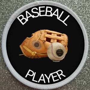 May include: A black and white circular patch with white text that reads "BASEBALL PLAYER". A brown baseball glove and a white baseball are in the center of the patch.