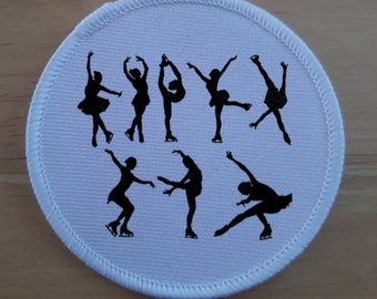May include: White round fabric patch with black silhouettes of figure skaters in various poses.