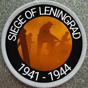 May include: A black and white circular patch with the text "Siege of Leningrad 1941-1944" around the edge. The center of the patch features a silhouette of soldiers in an orange-colored background.