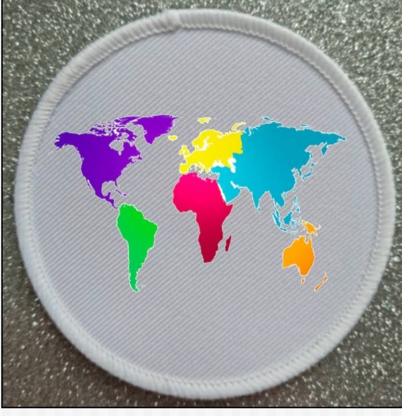 Peut inclure: Un &eacute;cusson circulaire blanc avec une carte du monde color&eacute;e imprim&eacute;e dessus. La carte est divis&eacute;e en continents avec des couleurs diff&eacute;rentes&nbsp;: violet pour l&rsquo;Am&eacute;rique du Nord, vert pour l&rsquo;Am&eacute;rique du Sud, rose pour l&rsquo;Afrique, jaune pour l&rsquo;Europe, bleu pour l&rsquo;Asie et orange pour l&rsquo;Australie.
