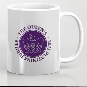 Könnte beinhalten: Weiße Keramiktasse mit einem violetten Kreisdesign. Der Kreis zeigt eine Krone und den Text "THE QUEEN'S PLATINUM JUBILEE 2022".