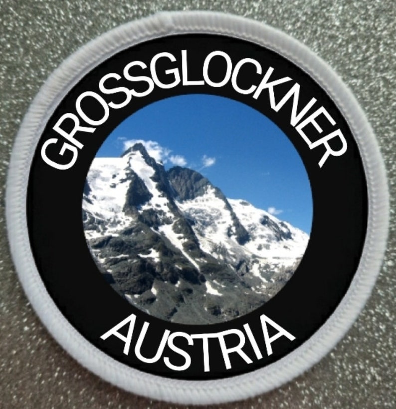 May include: A white round patch with black text and a photo of a mountain range. The text reads "GROSSGLOCKNER AUSTRIA".