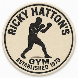 May include: Circular patch with the text "RICKY HATTON'S GYM ESTABLISHED 1978" in black. A black silhouette of a boxer is in the center, mid-punch. The patch has a beige background and a black border.