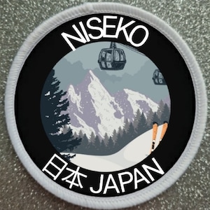 May include: A white round patch with a black circle in the center. The black circle has a white mountain scene with a ski lift and the text "NISEKO" at the top and "日本 JAPAN" at the bottom.