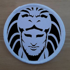 May include: White round patch with a black and white image of a person's face with a lion's mane.