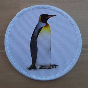Op de afbeelding: Een witte ronde patch met een zwart-witte keizerpinguïn met een gele borst die op een witte achtergrond staat.