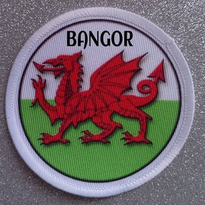 Peut inclure: Écusson circulaire blanc avec un dragon rouge sur fond vert et blanc. Le texte "BANGOR" est imprimé en noir en haut de l'écusson.