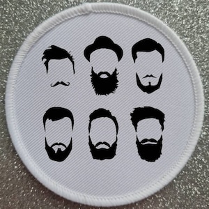 Puede incluir: Un parche redondo blanco con seis ilustraciones en blanco y negro de diferentes peinados y vello facial masculinos. Los peinados incluyen un tupé, un fedora, una raya lateral y un corte de pelo. El vello facial incluye un bigote, una barba de chivo y una barba.