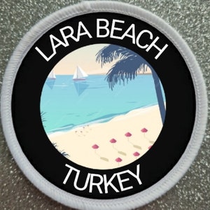 Puede incluir: Un parche redondo blanco con un círculo negro en el centro. El círculo negro tiene una imagen blanca de una escena de playa con palmeras, veleros y sombrillas rosas. El texto "LARA BEACH TURKEY" está escrito en blanco alrededor del círculo negro.