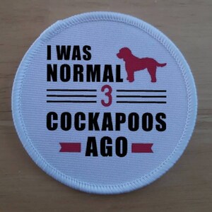 May include: White, circular patch with the text "I WAS NORMAL 3 COCKAPOOS AGO" in black. A red silhouette of a dog is above the number 3. The patch has a white stitched border.