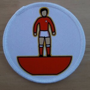 May include: A white round patch with a red and white soccer player standing on a red and gold half-circle.