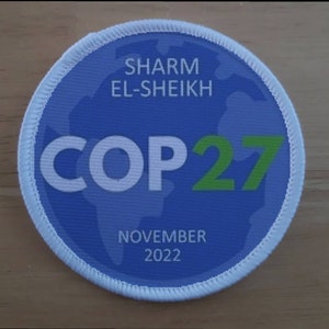 May include: A blue and white round patch with the text "SHARM EL-SHEIKH COP27 NOVEMBER 2022".