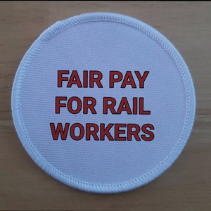 May include: White round fabric patch with red text that reads "FAIR PAY FOR RAIL WORKERS".