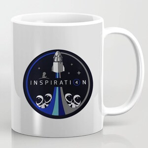 May include: White ceramic mug with a blue, gray, and white graphic of a rocket ship launching with the text "INSPIRATION 4" and four astronauts in space suits.