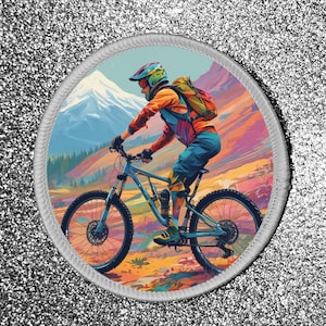 Könnte beinhalten: Eine farbenfrohe Illustration einer Person, die mit einem Mountainbike auf einem Weg mit einem Berg im Hintergrund fährt. Die Person trägt einen Helm und einen Rucksack. Das Fahrrad hat einen blauen Rahmen und schwarze Reifen.