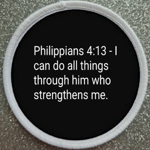 May include: Circular patch with a black centre and white border. The patch displays the text "Philippians 4:13 - I can do all things through him who strengthens me" in white lettering. The background has a glittery silver effect.