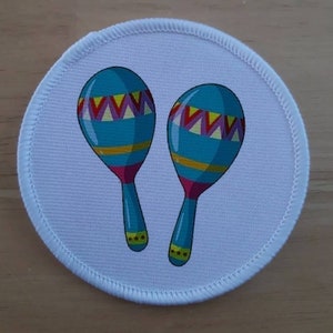 May include: A pair of maracas with blue, yellow, red and purple stripes. The maracas are on a white background.