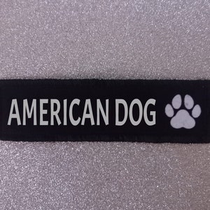 May include: Black fabric patch with white text that reads "AMERICAN DOG" and a white paw print.