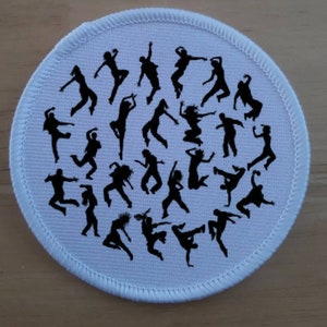 May include: White round fabric patch with black silhouettes of people dancing.