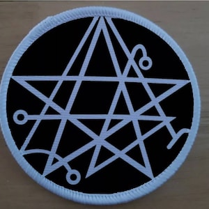 Könnte beinhalten: Weißer Stern mit einem komplexen geometrischen Design auf schwarzem Hintergrund. Der Stern ist von einem weißen Kreis mit weißem Rand umgeben.