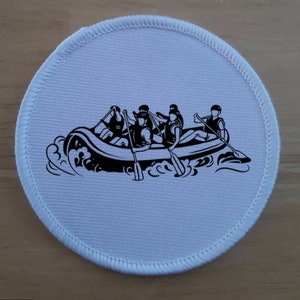 Puede incluir: Un parche redondo blanco con una ilustración en blanco y negro de un grupo de personas en una balsa remando río abajo.