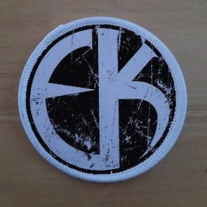 May include: White and black round patch with a distressed, stylized "FK" logo.