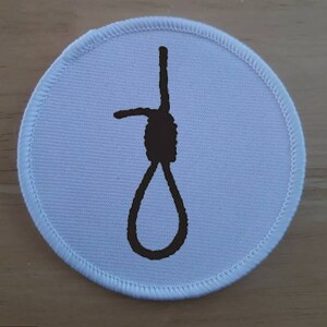 May include: White round fabric patch with a black outline of a noose.