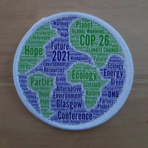 May include: A white circular patch with a green and purple word cloud depicting the Earth. The words include "COP 26", "Climate Change", "Hope", "Future", "2021", "Glasgow", "Parties", "Environment", "Ecology", "Energy", "Green", "Alternative", "Renewable", "Resources", "ONU", "Scotland", "Windpower", "Nature", "Planet", and "Global Warming".
