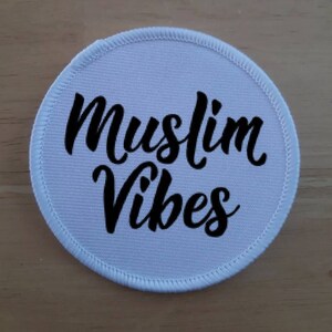 May include: White round fabric patch with black embroidered text that reads "Muslim Vibes".