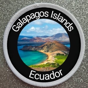 May include: A white circular patch with black text and a black circle in the center. The text reads "Galapagos Islands Ecuador". The black circle contains a photo of a beach with turquoise water and a rocky island.