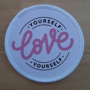 May include: White round fabric patch with black text that reads "Love Yourself" in a circle. The word "Love" is in pink cursive lettering.