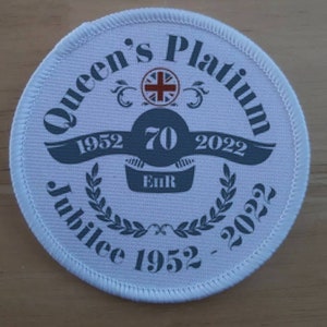 Könnte beinhalten: Runder weißer Patch mit einem grauen und weißen Design. Das Design zeigt den Text "Queen's Platinum Jubilee 1952 - 2022" und ein graues Banner mit dem Text "1952 70 2022" und "EIIR".