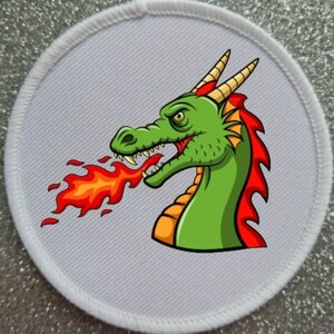 May include: A white circular patch with a green dragon with red horns and a red mane breathing orange flames.