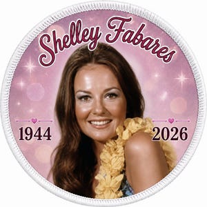 May include: A circular embroidered patch featuring a portrait of Shelley Fabares with long brown hair and a yellow floral lei. The background is a soft pink with sparkling light effects. The text reads Shelley Fabares, 1944, and 2026.