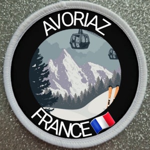 May include: A white and black circular patch with the text "AVORIAZ FRANCE" and a small French flag in the bottom right corner. The patch features a mountain scene with a ski lift and skiers.