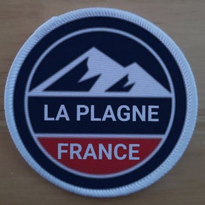 May include: White, blue, and red round patch with a white mountain range design and the text "LA PLAGNE FRANCE".