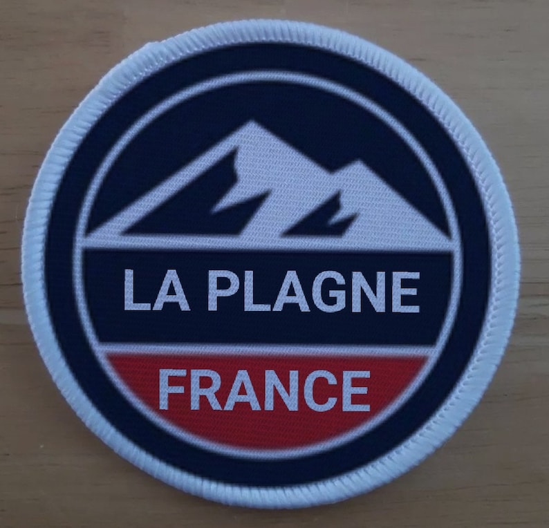 May include: A white, blue and red round patch with a white mountain range design and the text "LA PLAGNE FRANCE".
