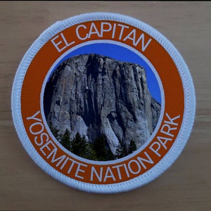 Könnte beinhalten: Ein runder weißer und orangefarbener Aufnäher mit dem Text "EL CAPITAN YOSEMITE NATIONAL PARK" und einem Foto von El Capitan im Yosemite-Nationalpark.