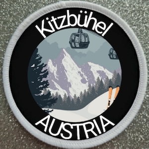 Könnte beinhalten: Ein weißer runder Patch mit schwarzem Text und einem Schwarzweißbild einer Bergszene mit Skiliften und Skifahrern. Der Text lautet "Kitzbühel Österreich".