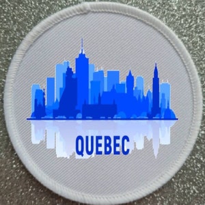 May include: White round patch with a blue silhouette of the Quebec City skyline and the word "QUEBEC" printed below.