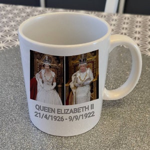 Könnte beinhalten: Weiße Keramiktasse mit einem Foto von Königin Elisabeth II. in zwei verschiedenen Outfits. Die Tasse trägt den Text "QUEEN ELIZABETH II 21/4/1926 - 9/9/1922" auf der Unterseite.
