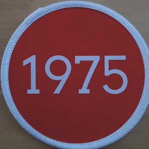 May include: A red circular patch with a white border and the number 1975 printed in white.