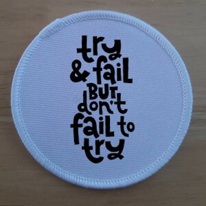 Può includere: Toppa rotonda in tessuto bianco con testo nero che recita "try & fail but don't fail to try".